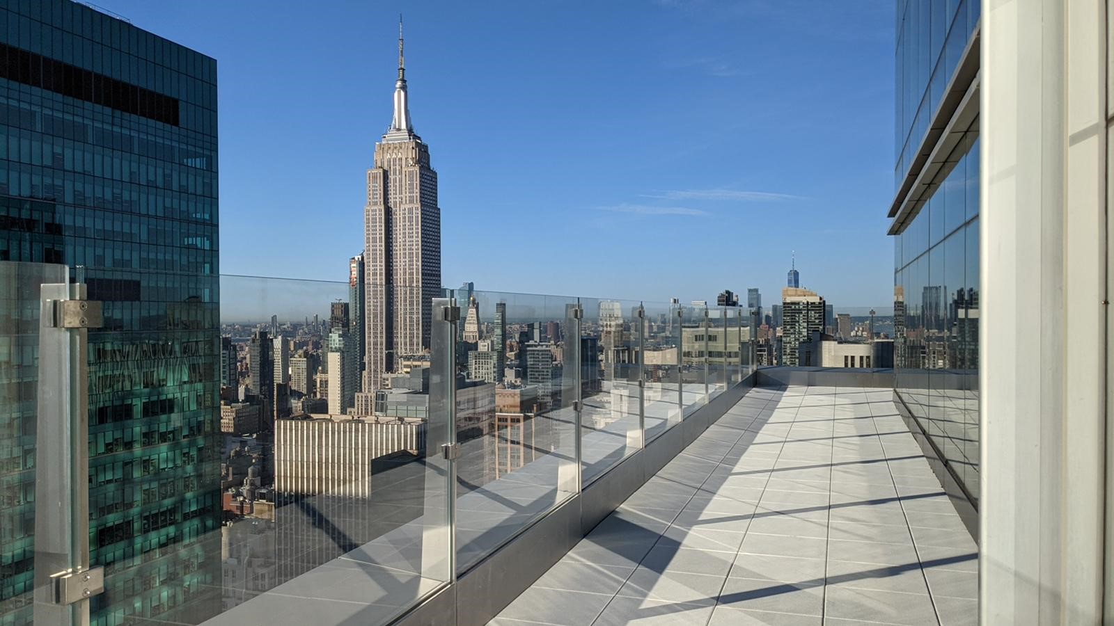Glasgeländer auf einem Hochhausbalkon mit Blick auf die Skyline von New York City