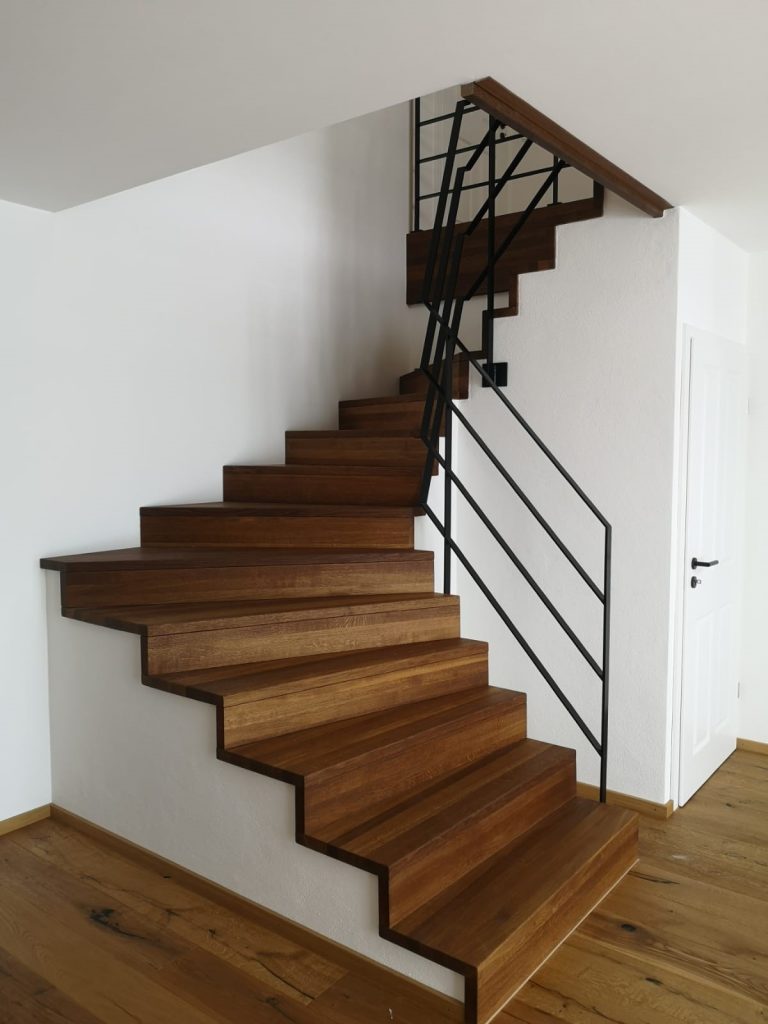 Seitenansicht einer Treppe mit Holzstufen und Metallgeländer in einem Privathaus