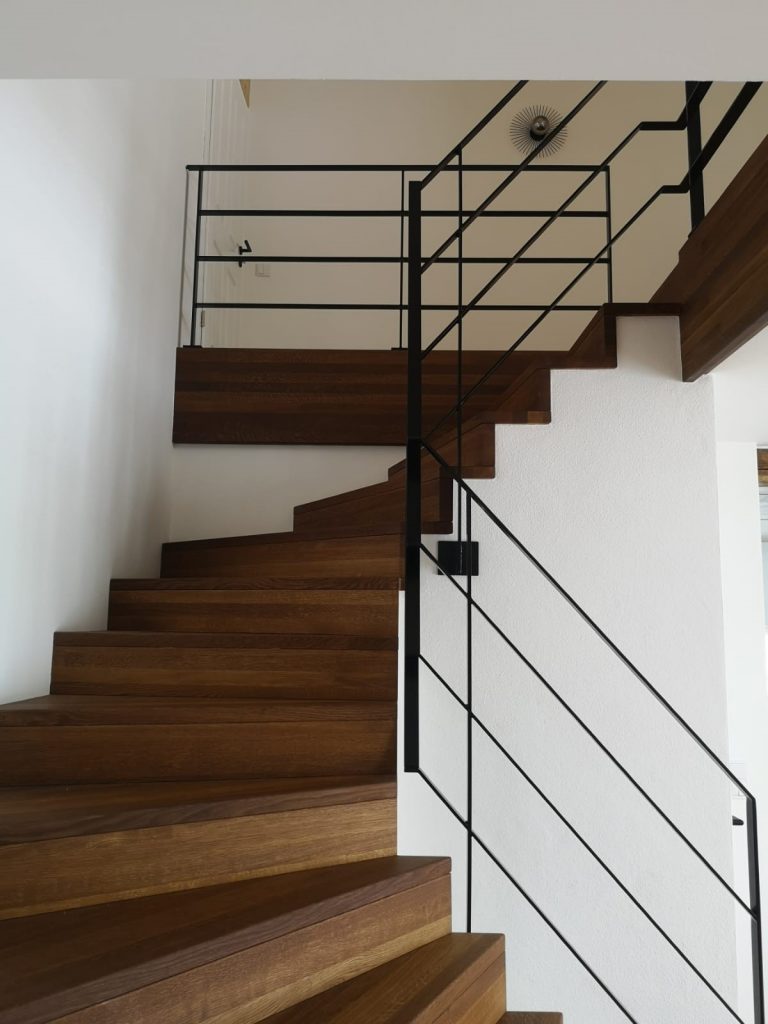 Frontansicht einer Treppe mit Holzstufen und Metallgeländer in einem Privathaus